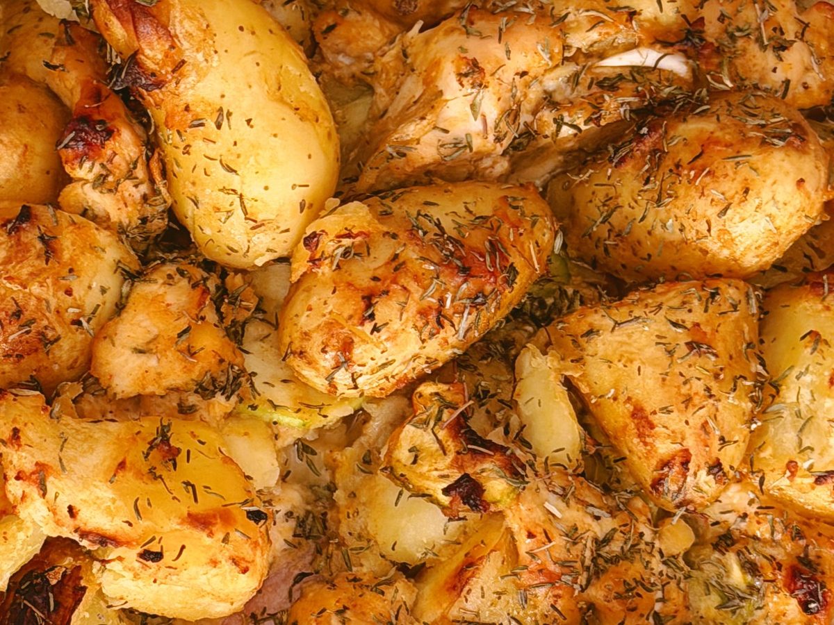 Greek lemon chicken and potatoes roasted together in one tray with herbs and lemon
